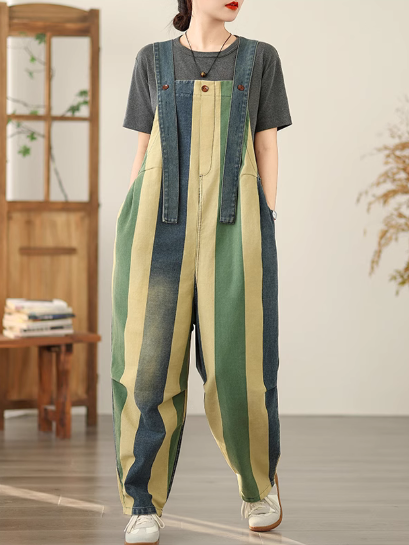 A woman wearing a striped colorful dungarees over a grey shirt with denim