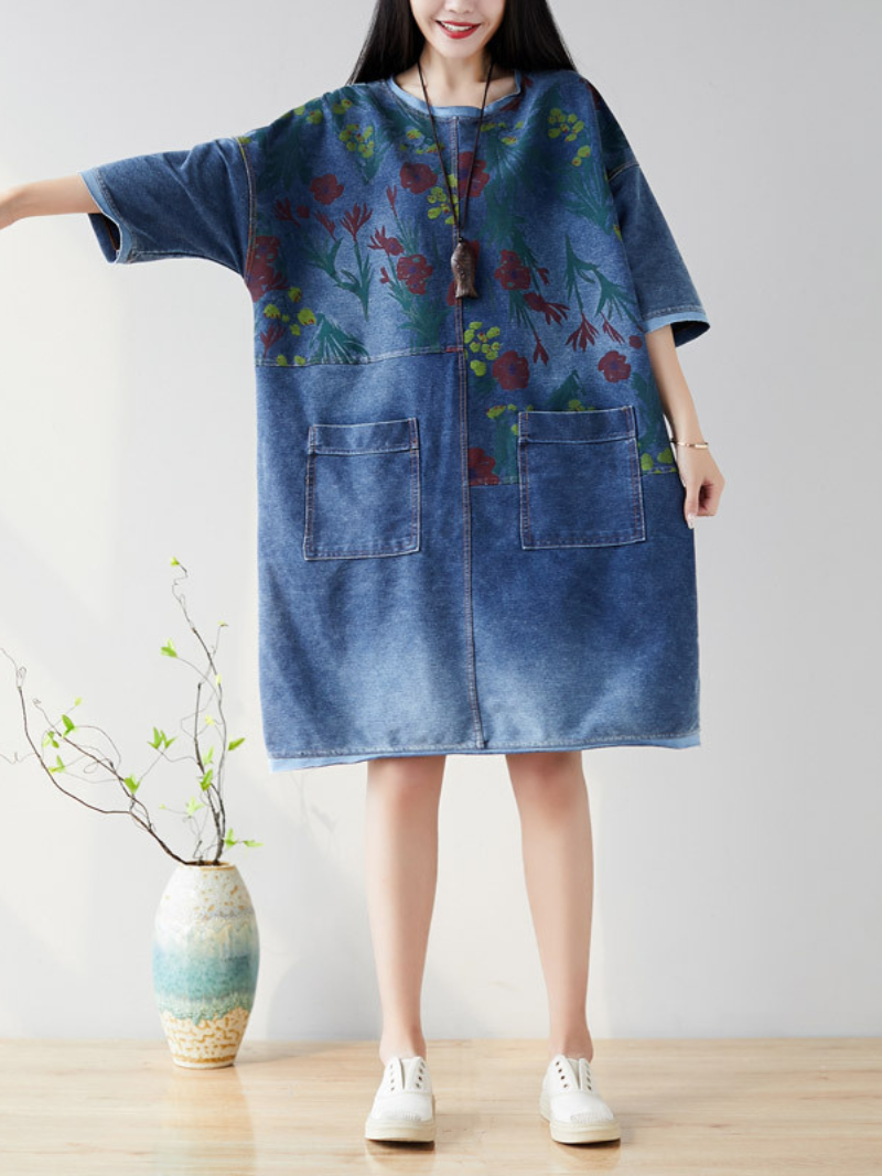 A woman wearing a casual floral midi dress with large pockets, in light blue denim color, 